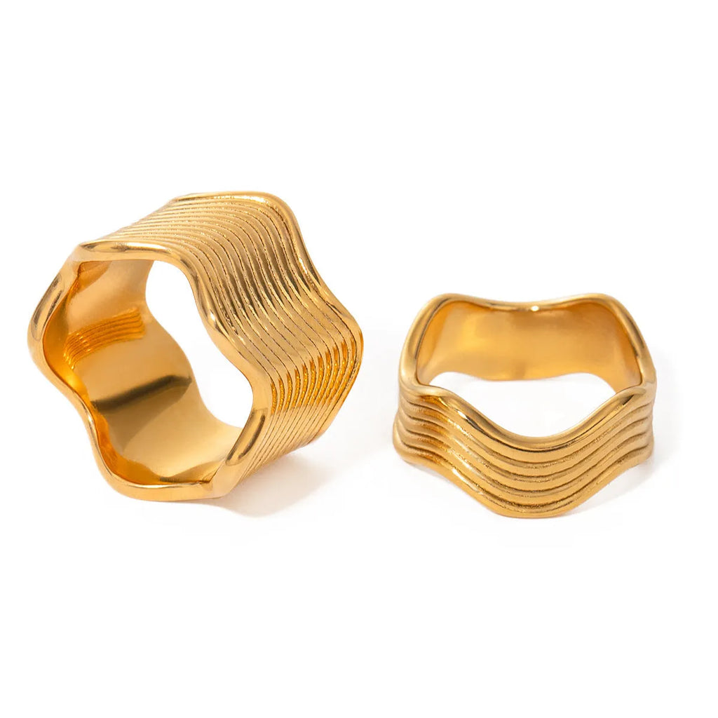 Stainless steel wide band ring with a geometric wave pattern in a metallic finish.
