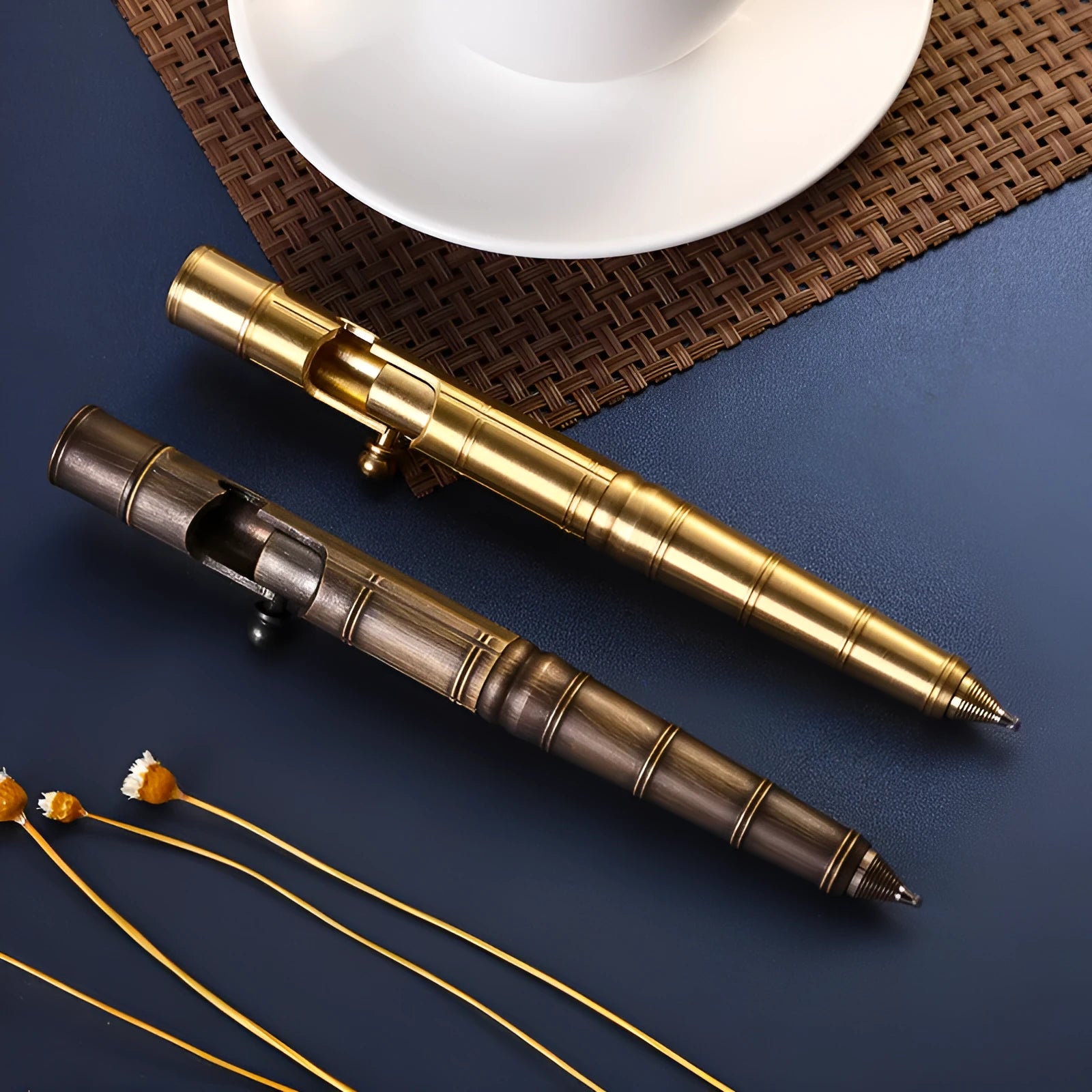 Retro brass tactical pen with a cylindrical barrel and bolt action mechanism on a dark background.