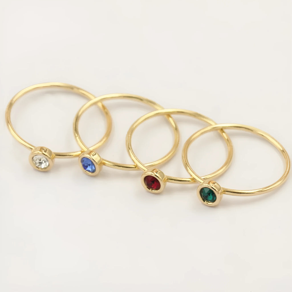 Gilded copper knuckle ring with a blue cubic zirconia stone on a model's hand.