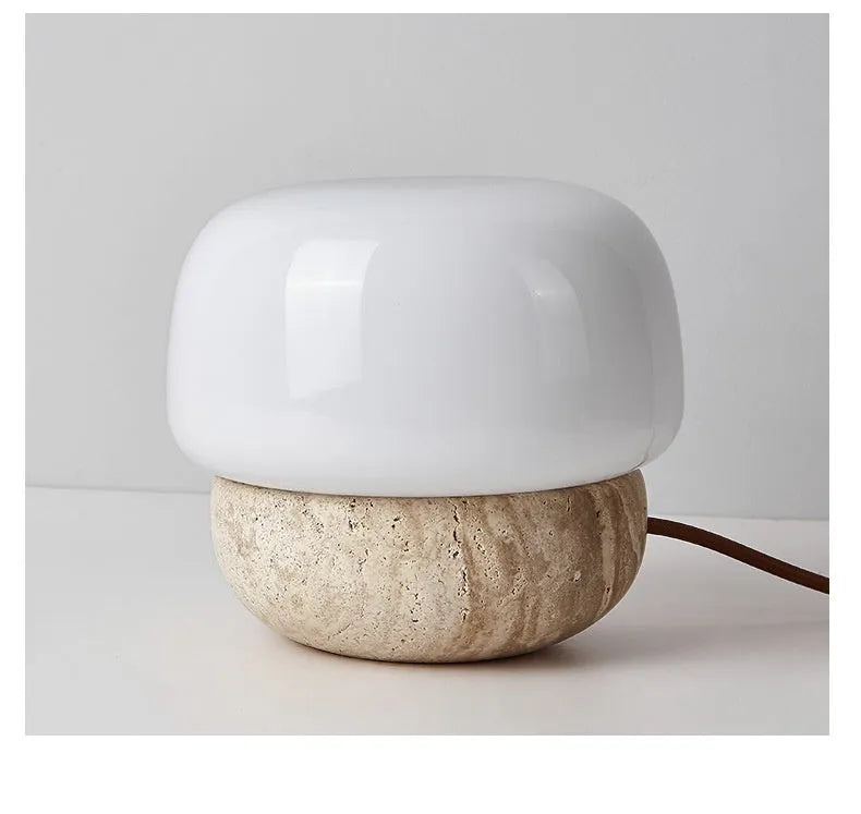 Cream-coloured retro style bedside lamp with a warm bulb on a table.