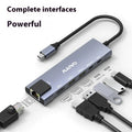 Aluminium Steam Deck six-in-one docking station with HDMI, USB, and Ethernet ports next to a handheld console.