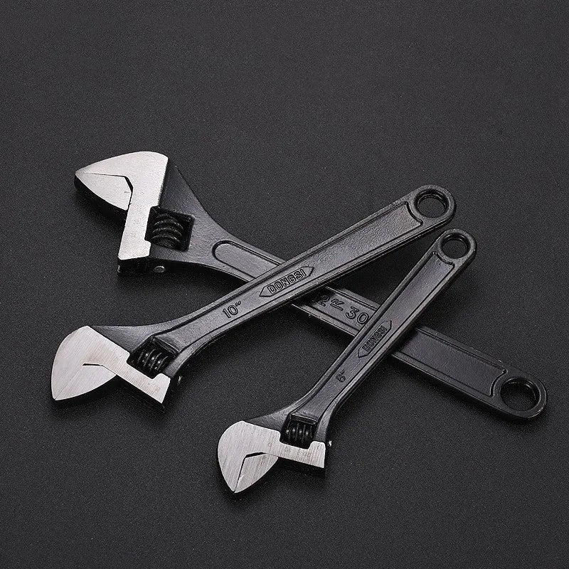 High carbon steel adjustable open-end spanner with black finish on a workbench.
