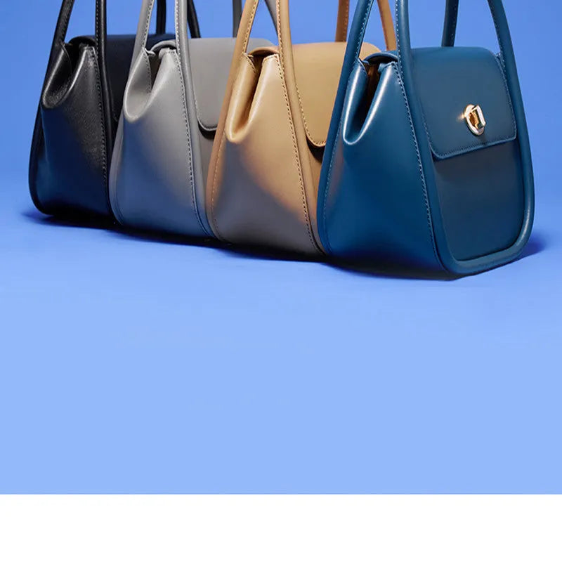 A wing-shaped cow leather tote bag with a buckle latch closure, shown in blue with a single cross-body strap.