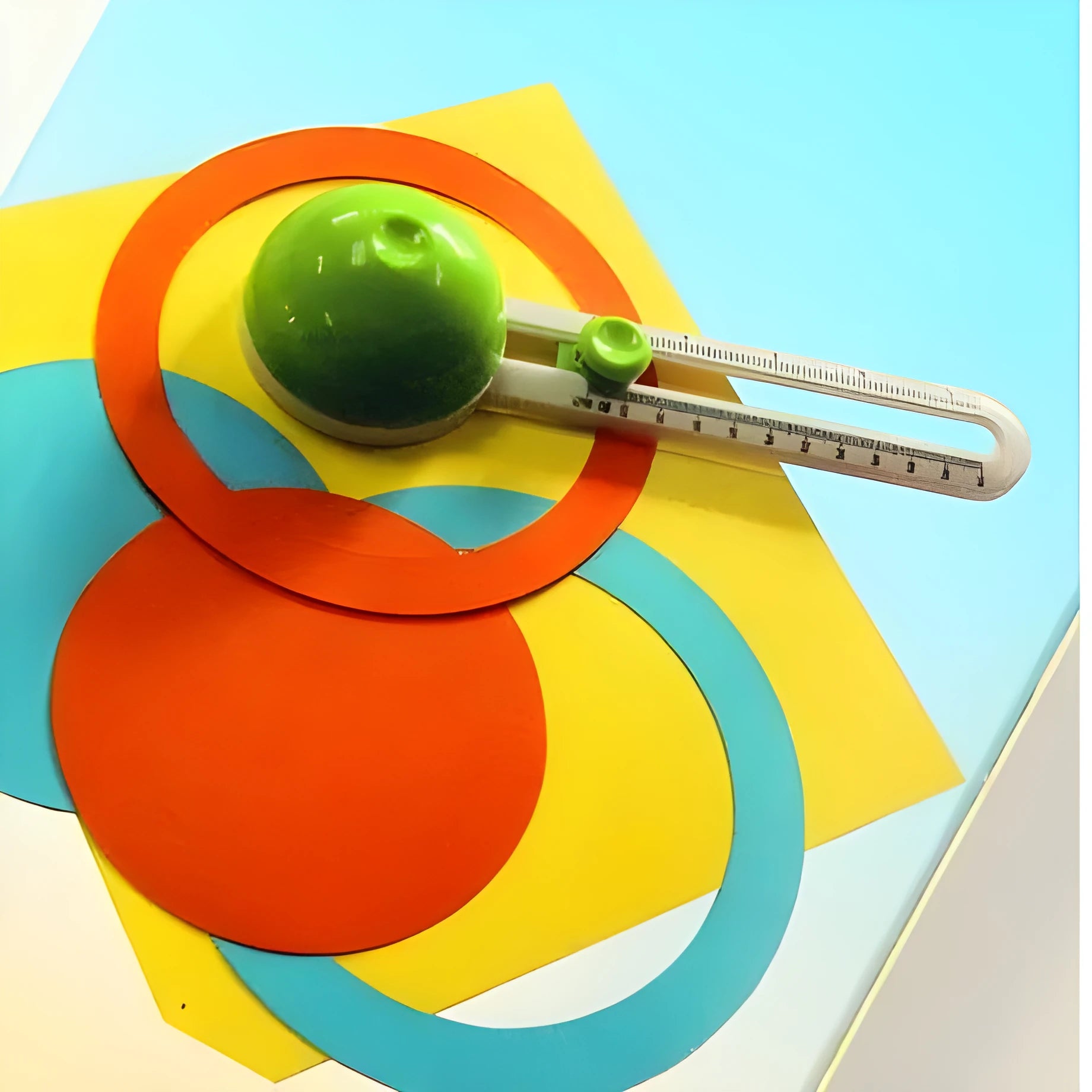 Orange and green plastic round paper cutter for A3 sheets on a table.