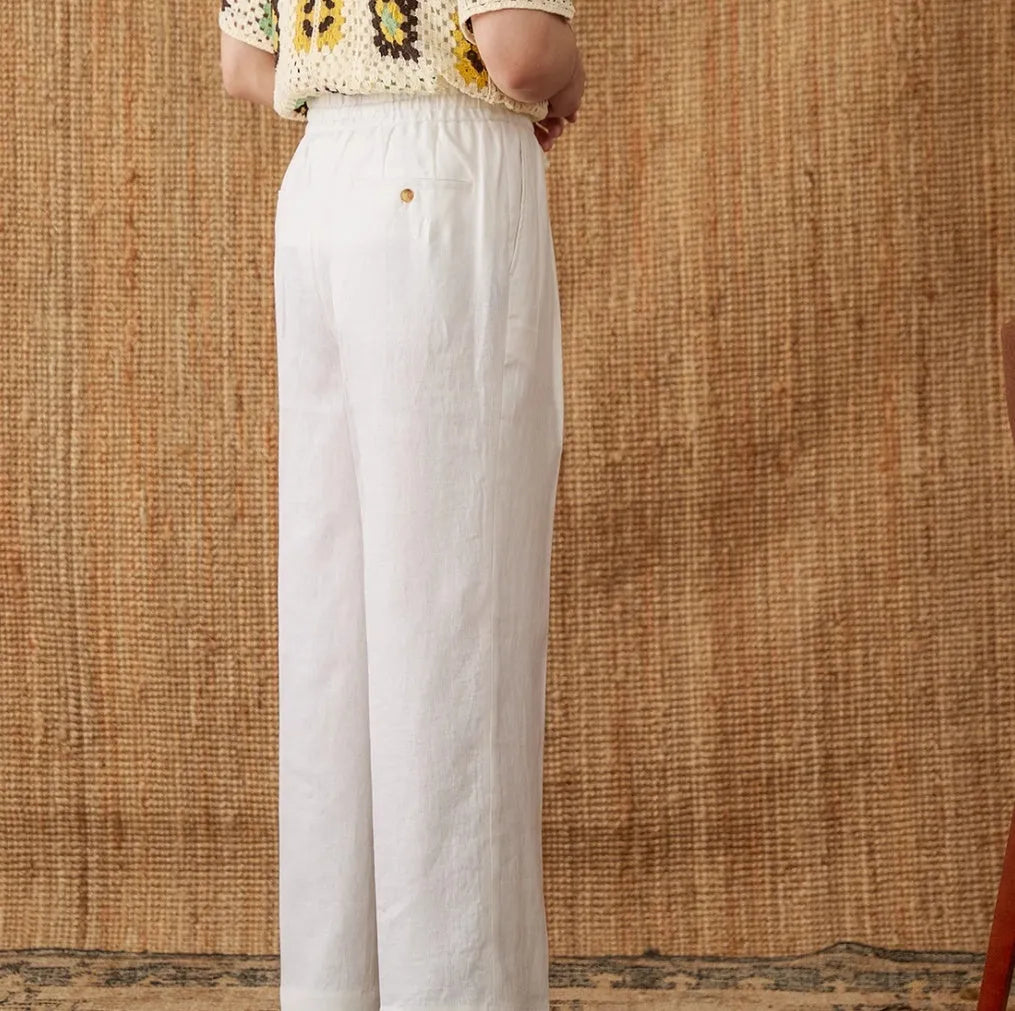 Linen high waist trousers with elasticated waistband in a straight-leg fit on a hanger.