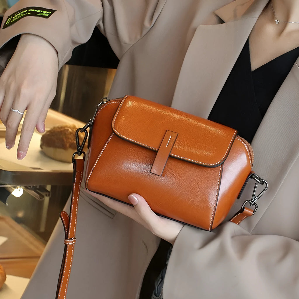 Brown women's crossbody messenger bag in soft oil wax leather with shell shape and visible sewing detailing