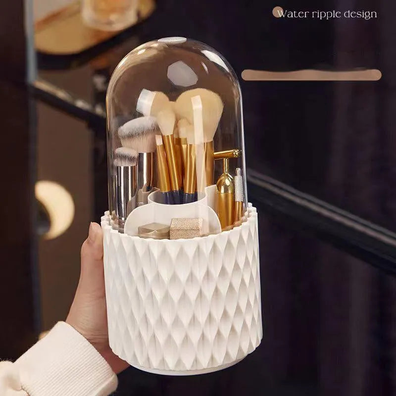 White acrylic rotating makeup brush holder with transparent body and a grey dust cover on a desk.