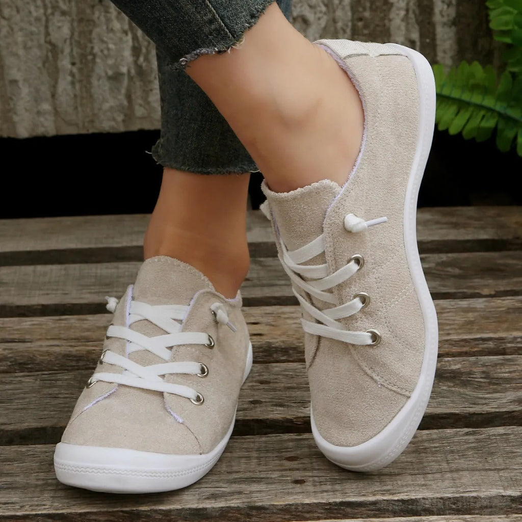 Creamy-white low-top fabric sneaker for women with a rubber sole on a neutral background