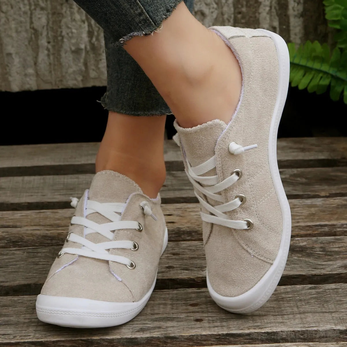 Creamy-white low-top fabric sneaker for women with a rubber sole on a neutral background
