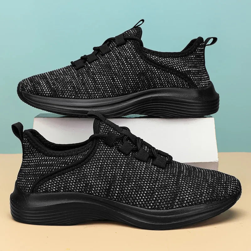 Women's low-top black casual sneakers with mesh upper and lace-up front on a grey background.
