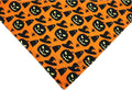 Black and orange reversible Halloween dog bandana with pumpkin and spider web patterns, adjustable for necks up to 16 inches