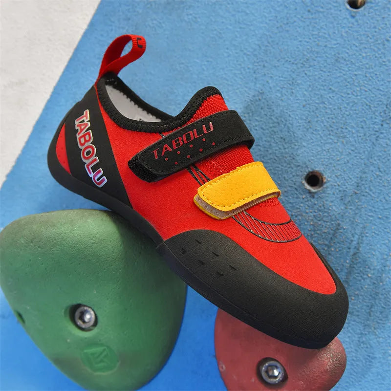 Beginner rock climbing shoes with Velcro strap and rubber sole in black and red colour.
