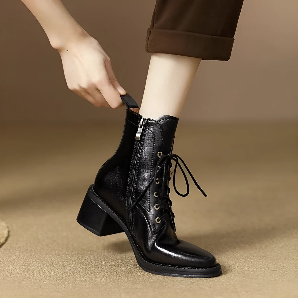 Women's black pointed-toe ankle boots with a short tube and block heel on a plain background