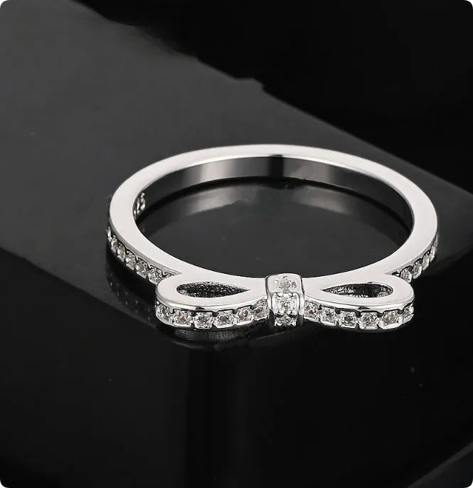 Silver couple style bow ring with rhinestone zircon crystals on finger showing electroplated finish