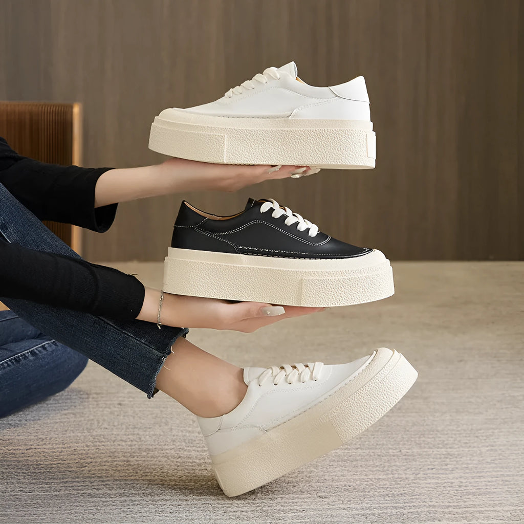 Black and white women's embossed leather platform sports shoes with a round toe and rubber sole.