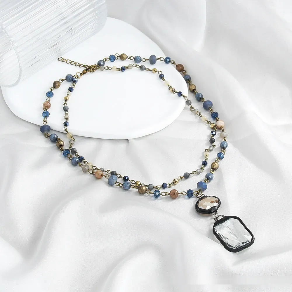 Tribal style two-layer necklace with glass and stone pendants in beige and blue on adjustable chain