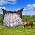 Black woven PE rope grid feeding bag hung on a fence, suitable for horses and cattle.