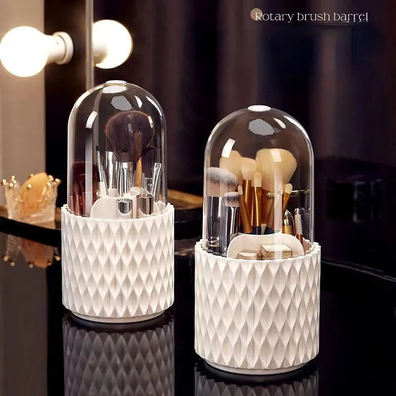 White acrylic rotating makeup brush holder with transparent body and a grey dust cover on a desk.