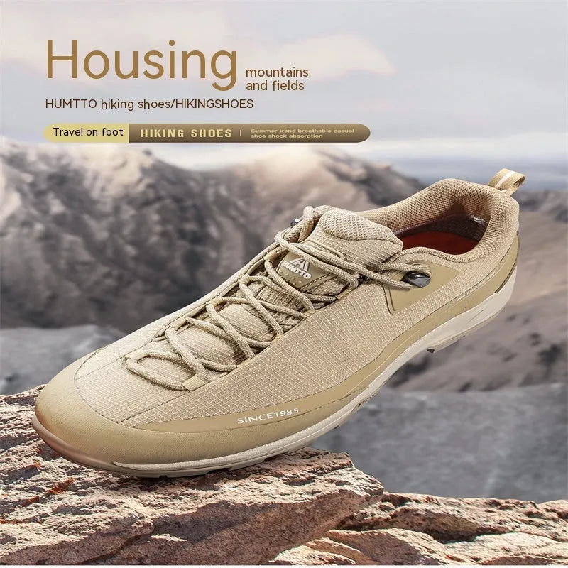 Men's low-top hiking boots in dark grey with round toe and front lace-up design on a rocky trail.