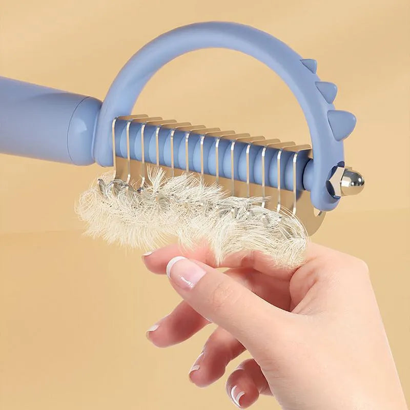 Blue dinosaur-shaped self-cleaning pet grooming brush with double-sided stainless steel pins on a white background.