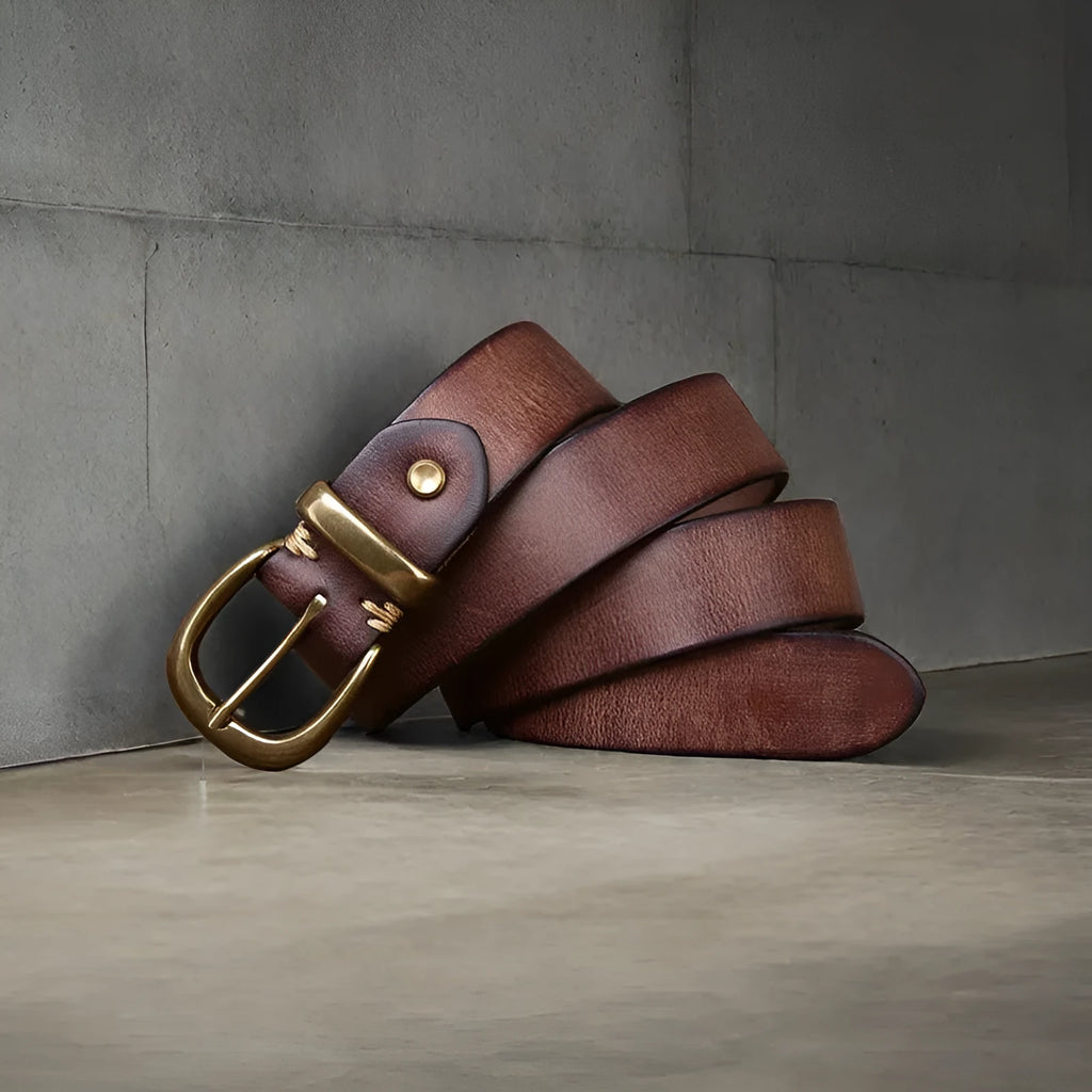 Men's brown genuine cowhide leather belt with a copper pin buckle on a jeans background.