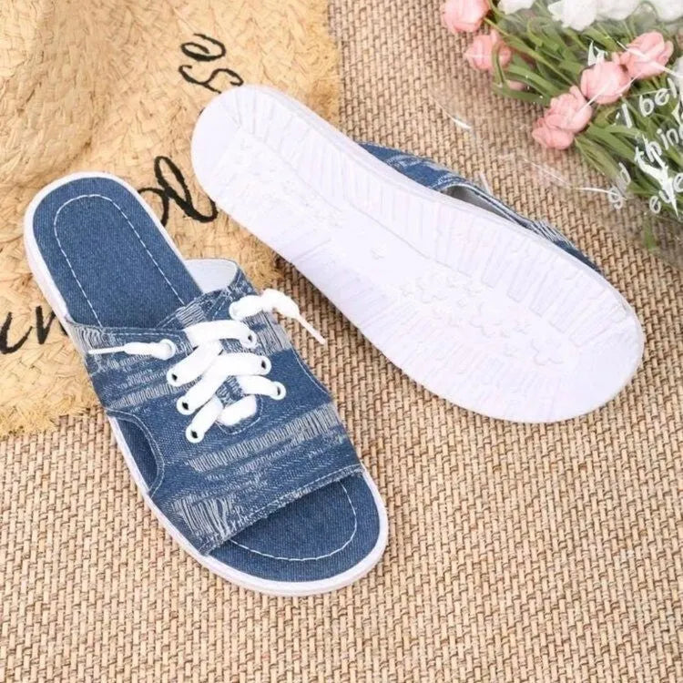 Blue women's Roman-style flat canvas slippers with a rubber sole, shown from the side.