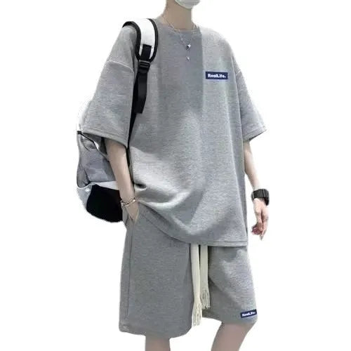 Man wearing a grey waffle-textured short sleeve top and matching shorts from the leisure sports suit set.