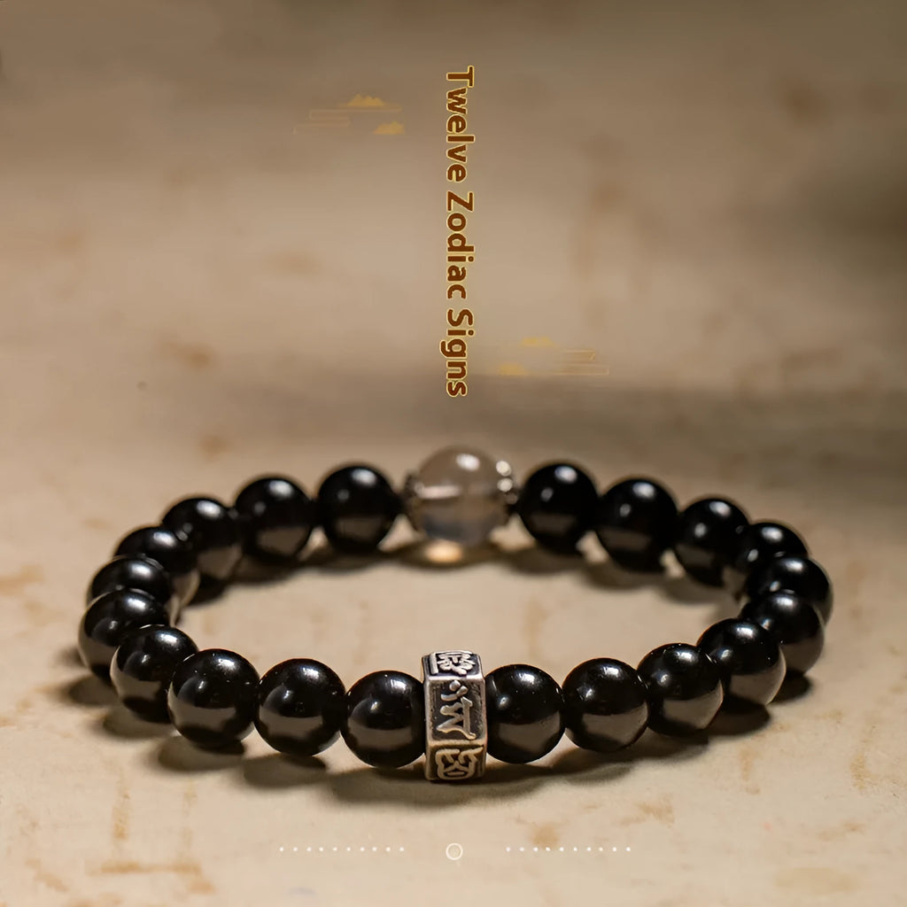 Close-up of an 8mm obsidian beaded bracelet with zodiac and Buddhist bodhisattva designs.