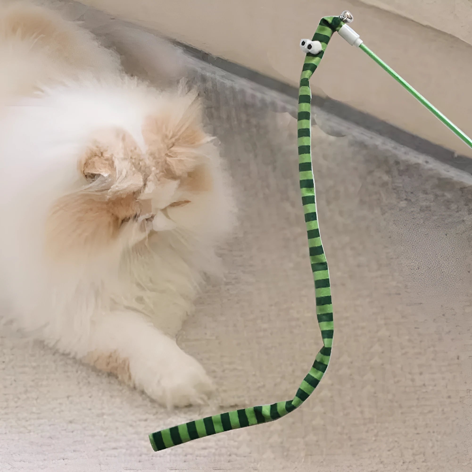A colourful cat teaser wand with a long plush strip and a bell, held by a person.