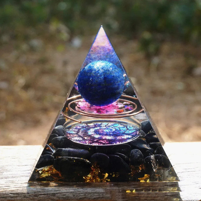A 6cm high clear resin pyramid ornament filled with colourful crystal gravel on a wooden surface.