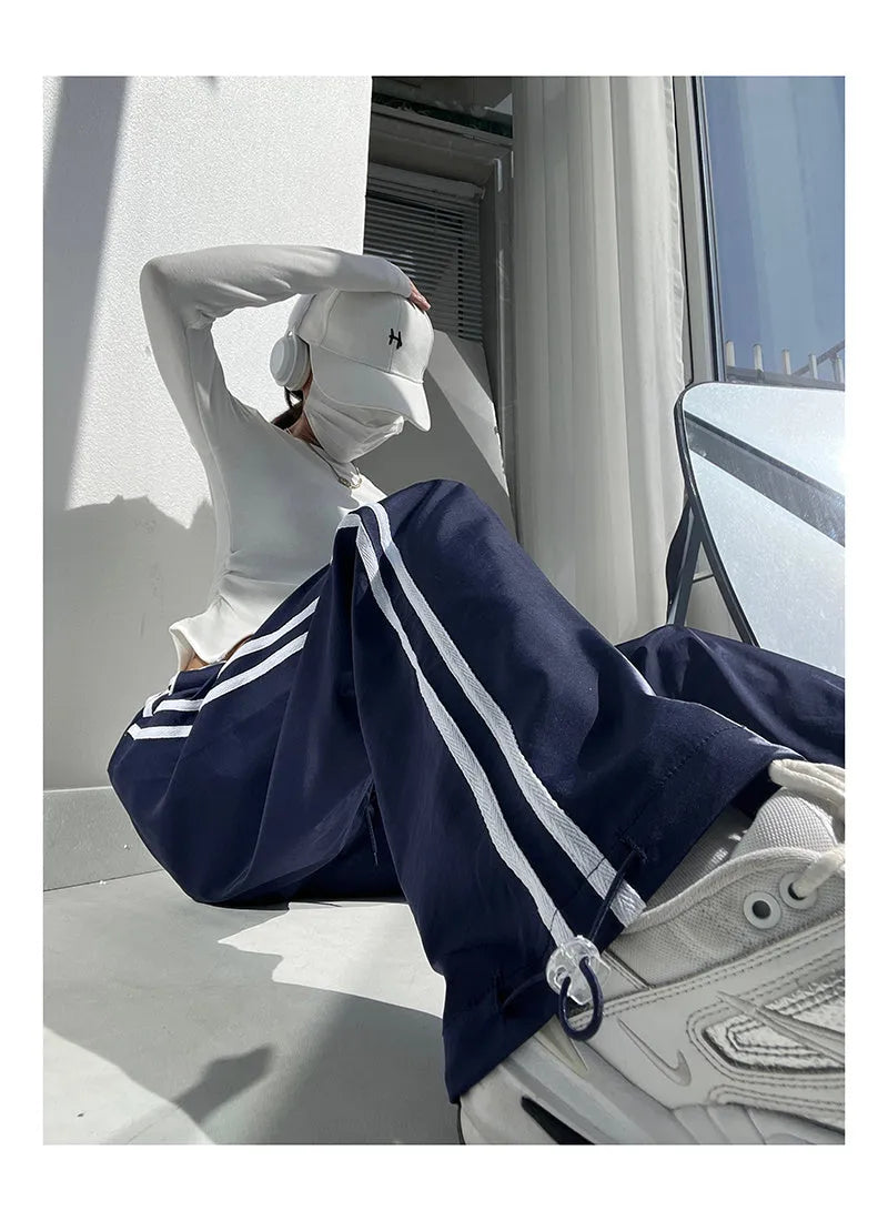 Navy blue loose straight-leg trousers with white parallel ribbon detail on the legs.