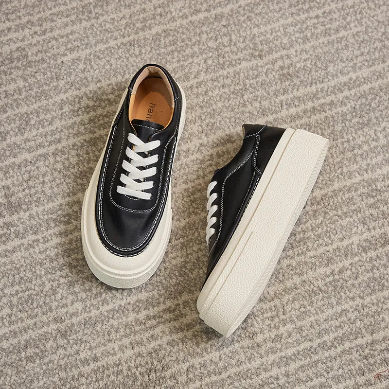 Black and white women's embossed leather platform sports shoes with a round toe and rubber sole.