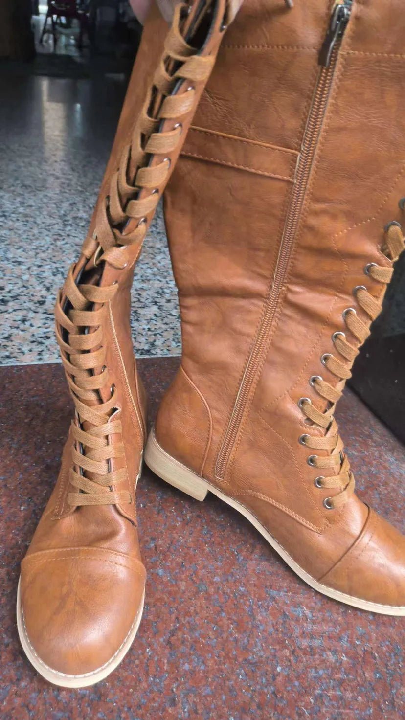 Women's black cross strap knight boots made from artificial PU, showing the ankle strap detail.
