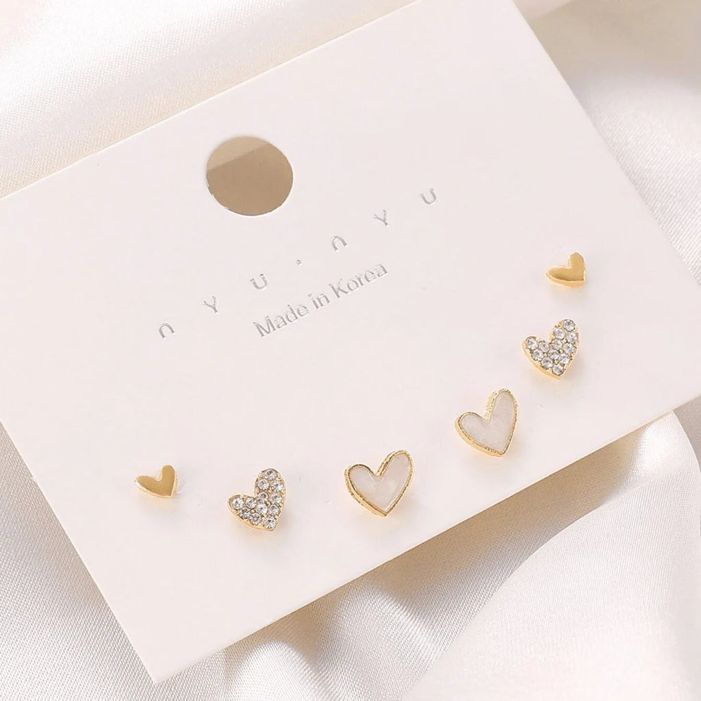 Set of three pairs of heart-shaped alloy earrings in gold, black, black and white, and pink colours.