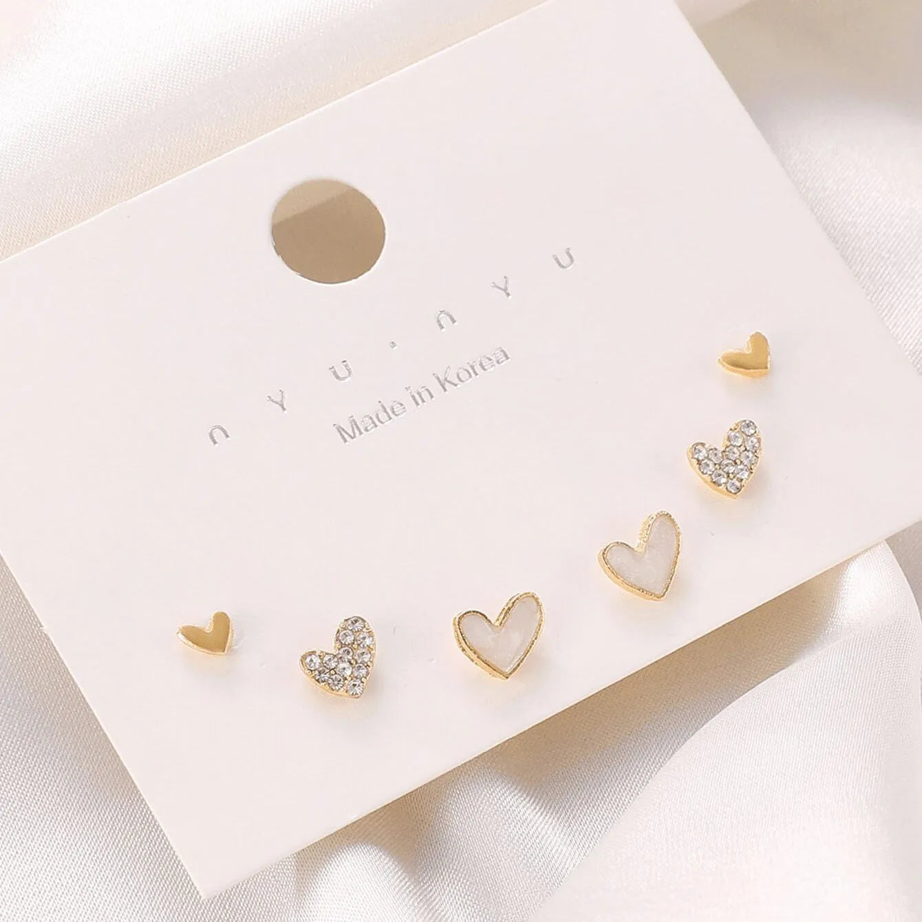 Set of three pairs of heart-shaped alloy earrings in gold, black, black and white, and pink colours.