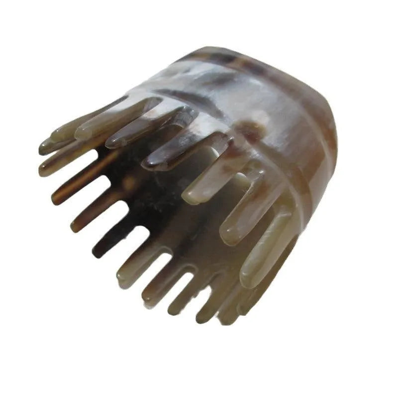 White buffalo horn comb with wide teeth on one side and pointed tips for head meridian massage.