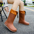 Solid-colour women's PVC rain boot with a non-slip sole in apricot, black, brown, or pink.