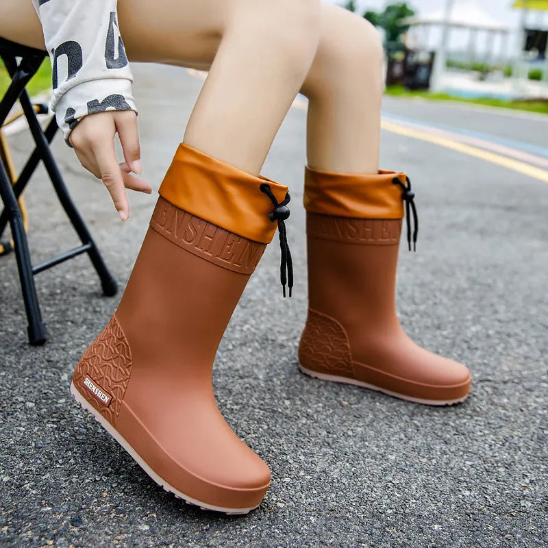 Solid-colour women's PVC rain boot with a non-slip sole in apricot, black, brown, or pink.