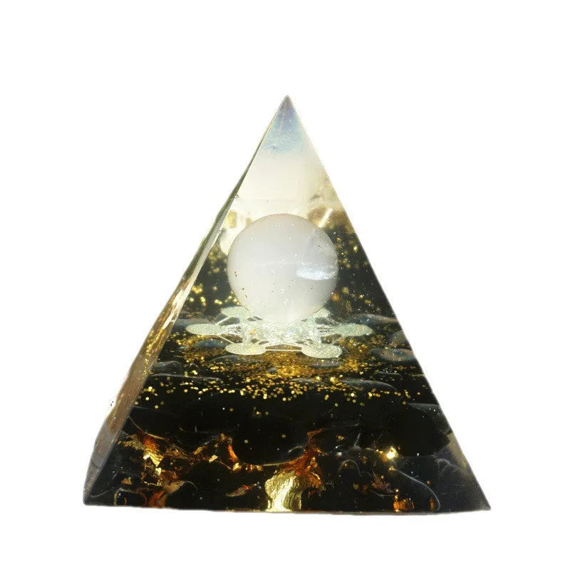 A 6cm high clear resin pyramid ornament filled with colourful crystal gravel on a wooden surface.