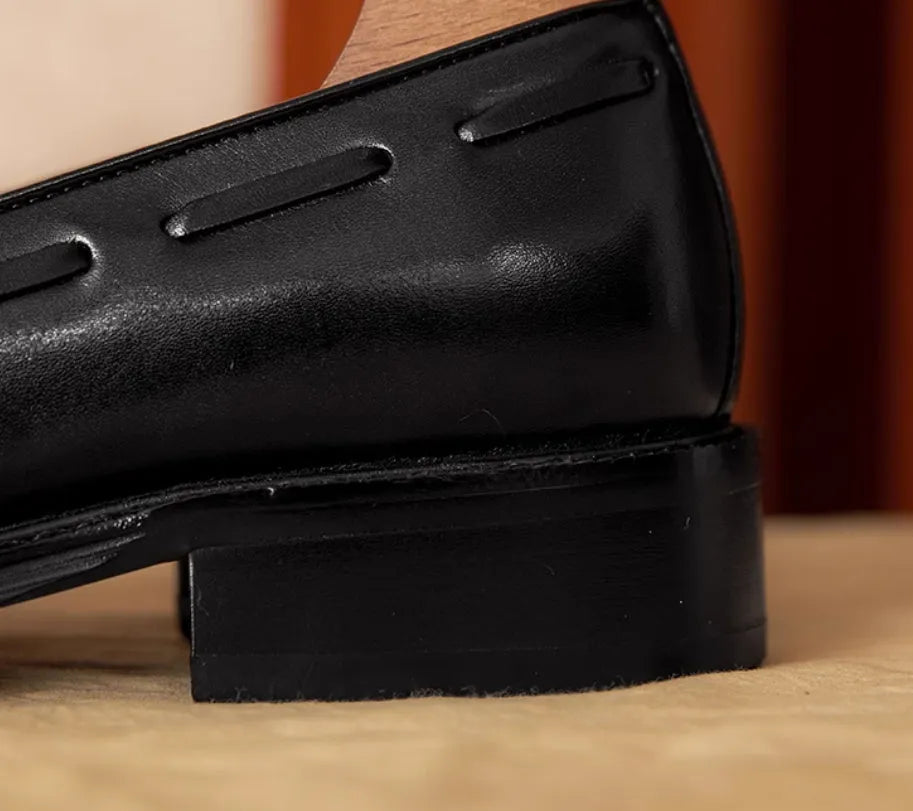 Men's black genuine leather slip-on loafers with fringed detailing and a rubber sole, shown from a side view.