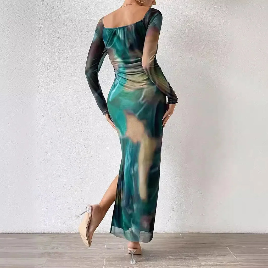 A woman wearing a long green mesh fishtail dress with pleats, a square collar, and a gradient colour print.
