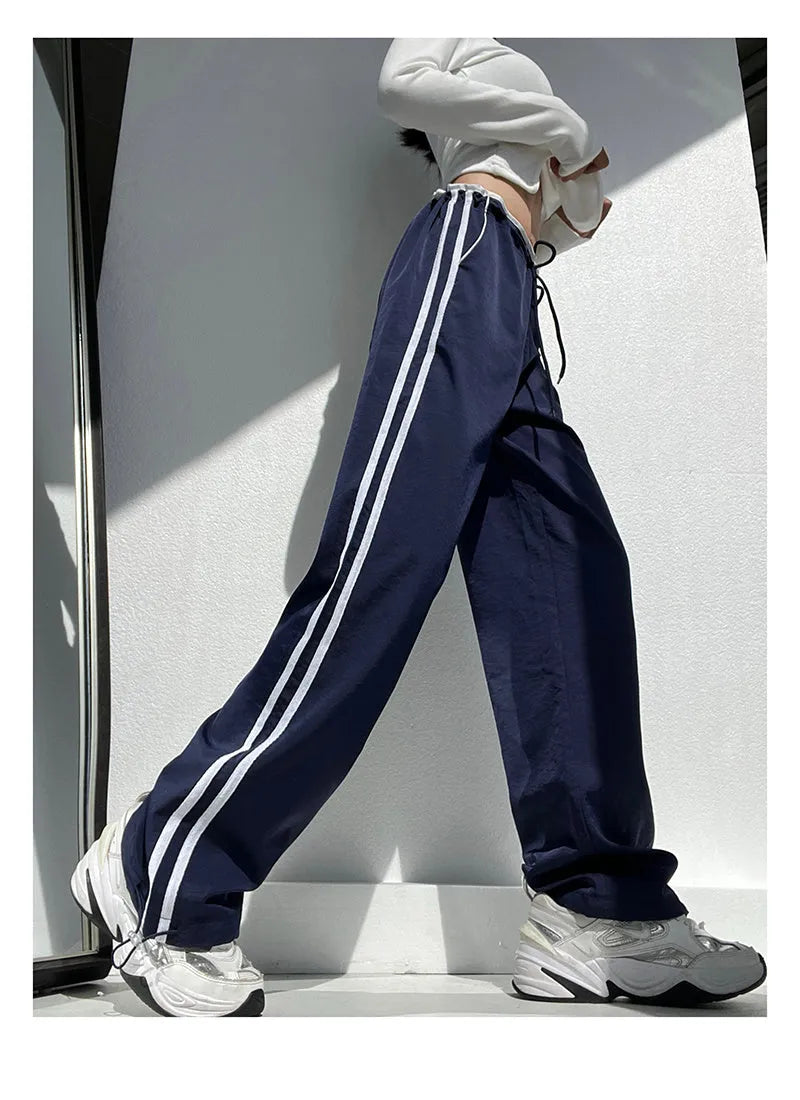 Navy blue loose straight-leg trousers with white parallel ribbon detail on the legs.