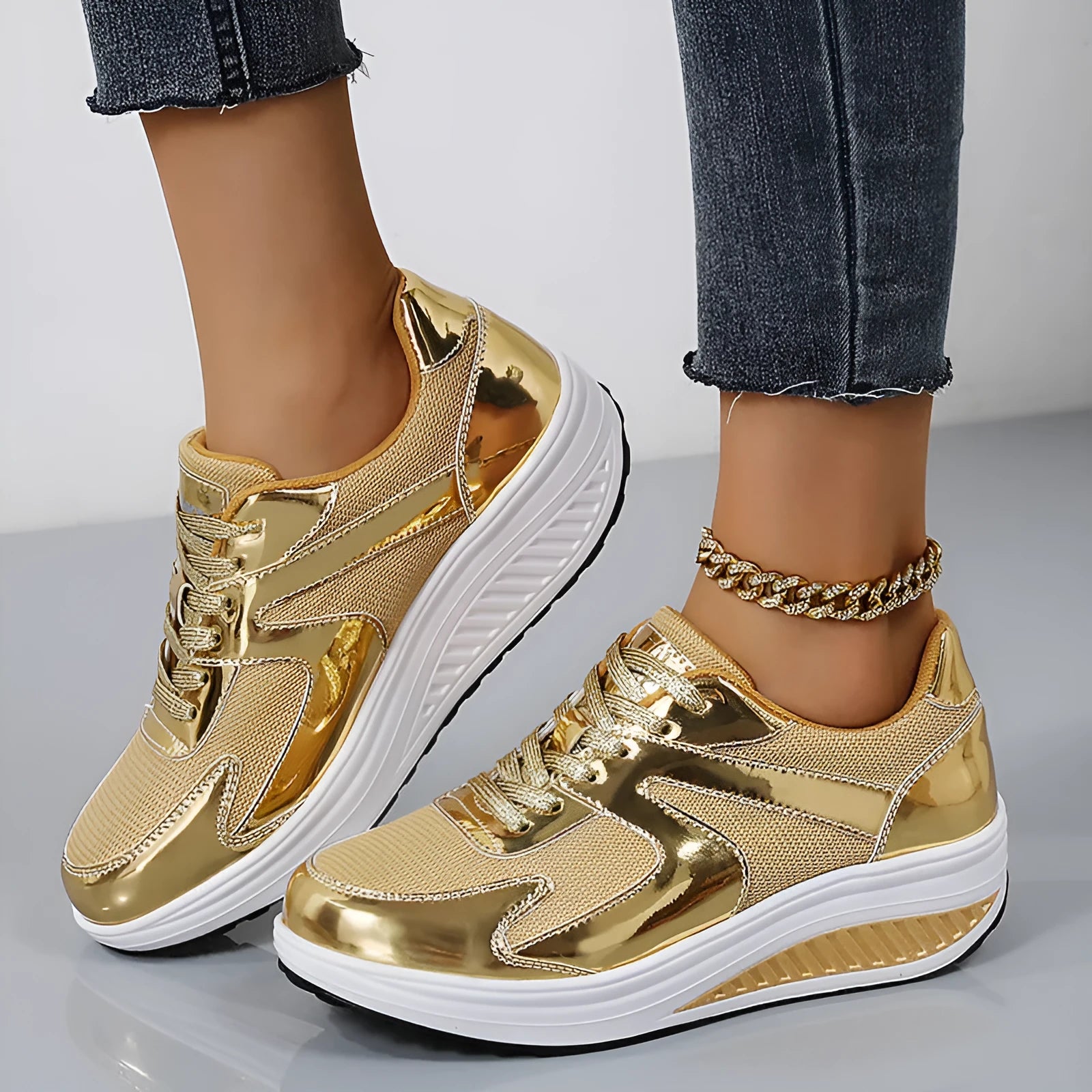 Women's gold patent leather mesh sports shoes with cross straps and platform sole.