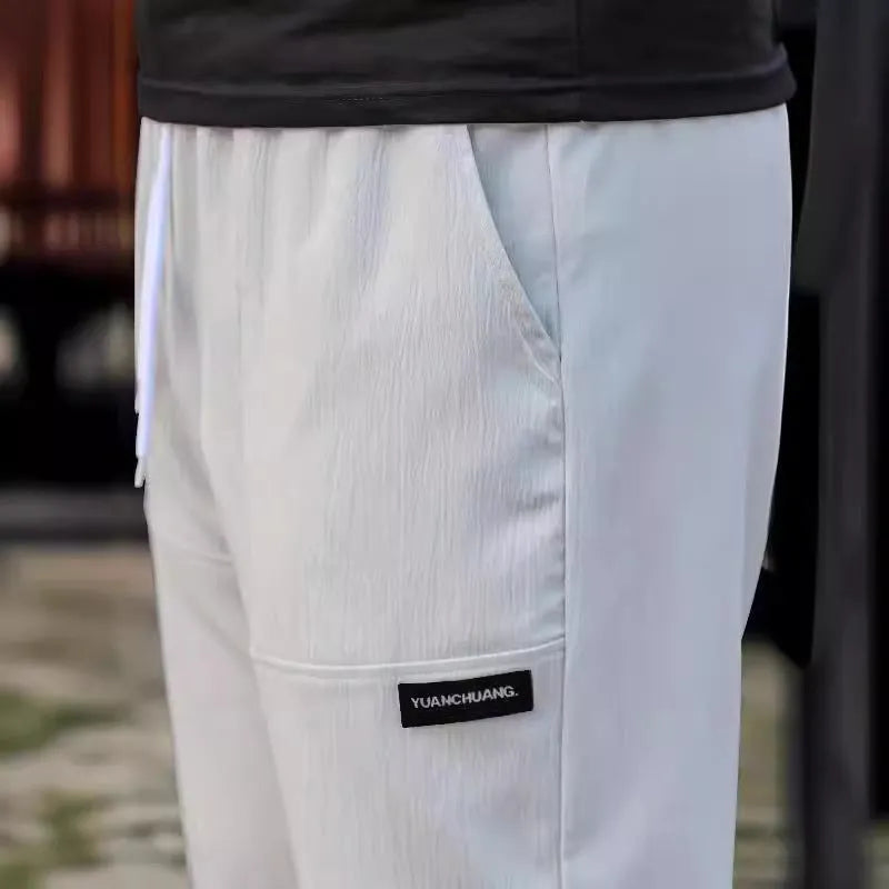 Men's polyester trousers for spring and autumn in light grey, shown in a casual setting.