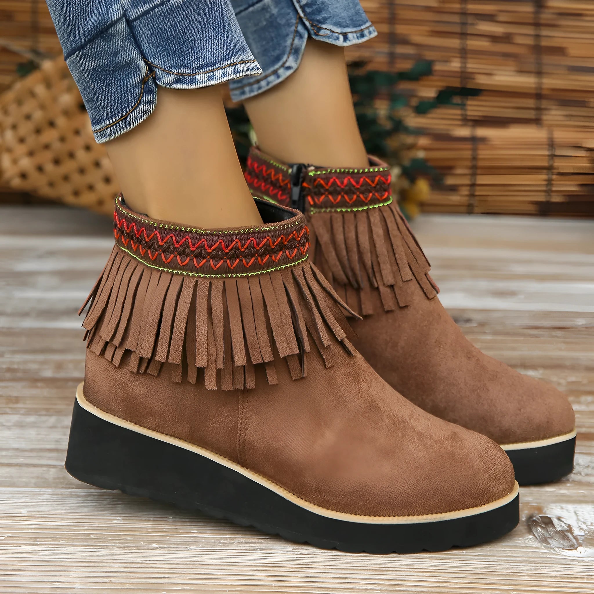 Women's black suede ankle boot with wedge heel, platform sole, side zip, and tassel detail.