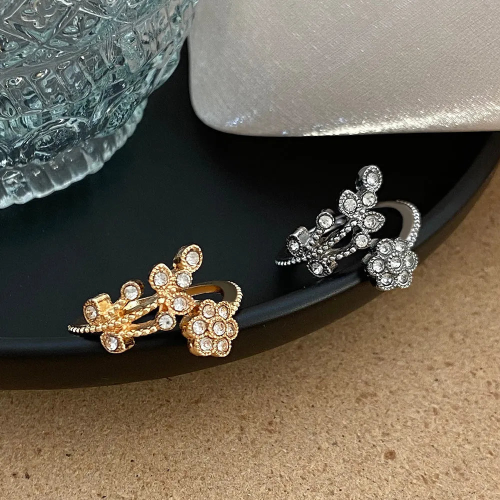 Women's open ring with flower and leaf design on a copper base with a diamond finish.