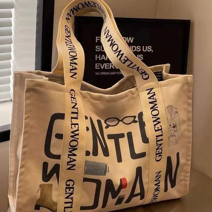 Large canvas tote shoulder bag with printed design in black letter, coloured letter, and pattern styles.