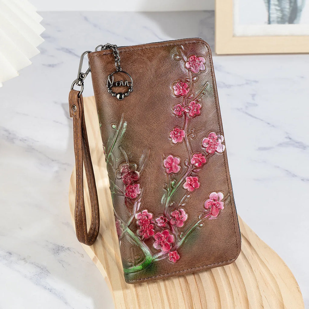 Black embossed floral handbag with hand-painted details and a zipper closure.