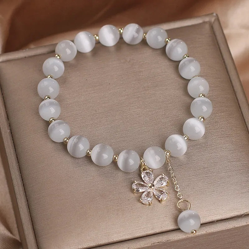 White cat's eye crystal bracelet with flower tassel and safety buckle for women.