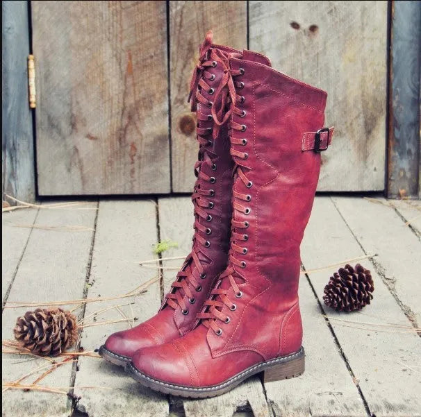 Women's black cross strap knight boots made from artificial PU, showing the ankle strap detail.